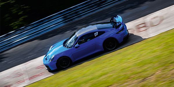 Blauer Sportwagen fährt über die Nordschleife.